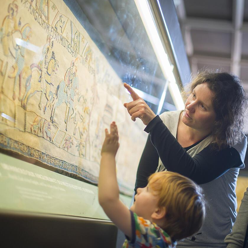 a parent and child looking at the tapestry